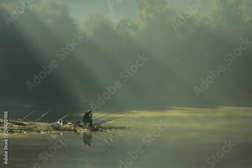 Serbia, Novi Sad; October 15th 2017: Fisherman in the early foggy morning with sunbeams