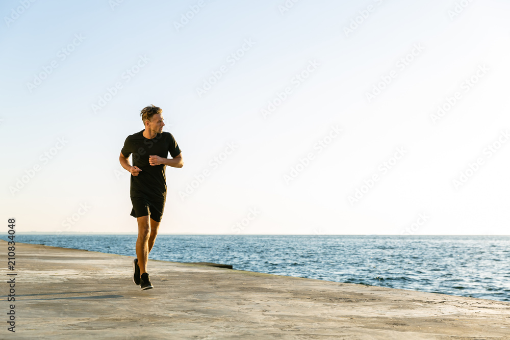 sporty adult joger running on seashore in morning sporty adult joger running on seashore in morning