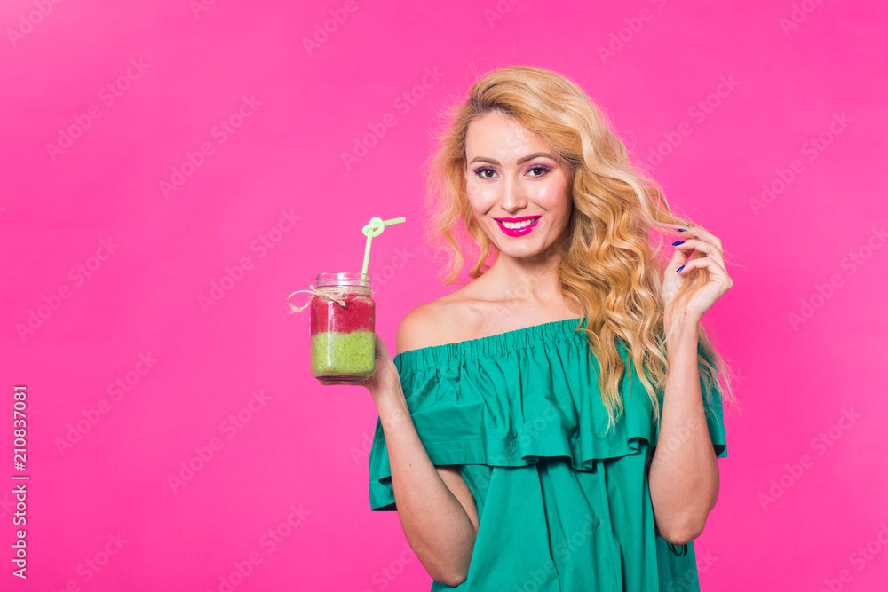 Young beautiful woman with green smoothie on pink background with copyspace Young beautiful woman with green smoothie on pink background with copyspace