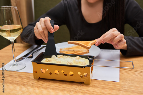 the girl tastes cheese raclette in a cafe. swiss food. cheese raclette with mushrooms on coupelles - special small skillet for a raclette photo