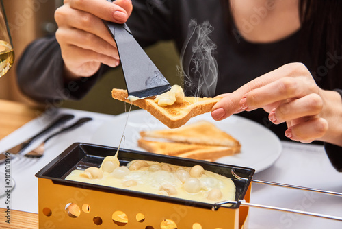 Photography the girl tastes cheese raclette in a cafe