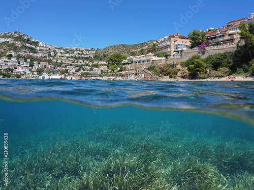 Coastal town in Spain on the Costa Brava and seagrass meadow underwater, split view above and below water surface, Mediterranean sea, Roses, Catalonia, Girona
