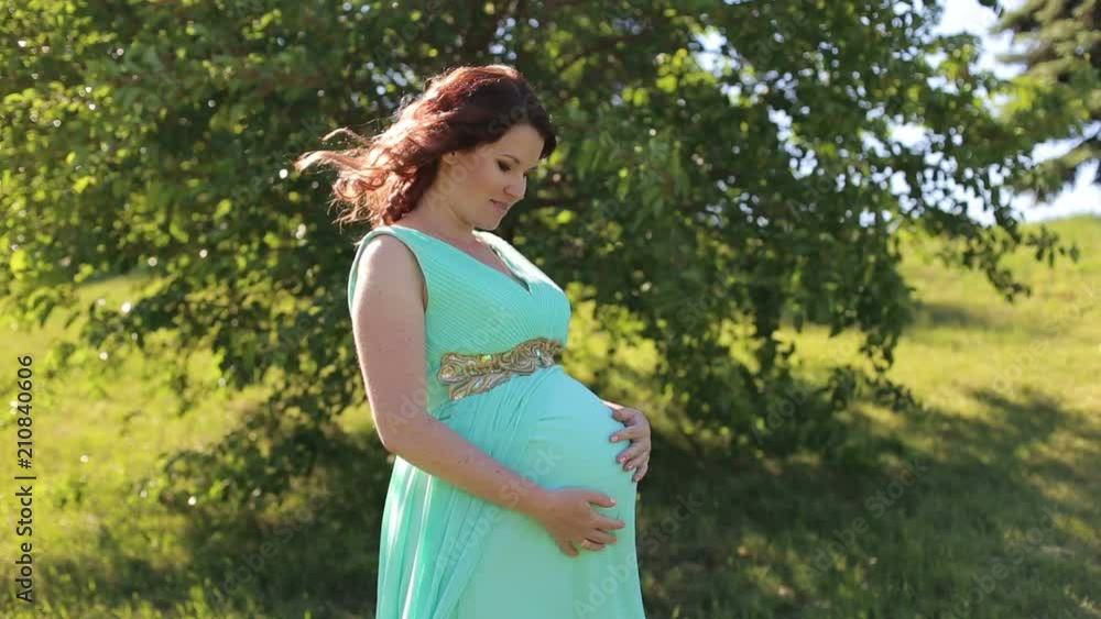 Portrait of beautiful pregnant woman in turquoise dress in the flowering spring park. Portrait of beautiful pregnant woman in turquoise dress in the flowering spring park.
