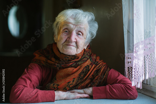 Portrait of an elderly woman sitting at home at the table.