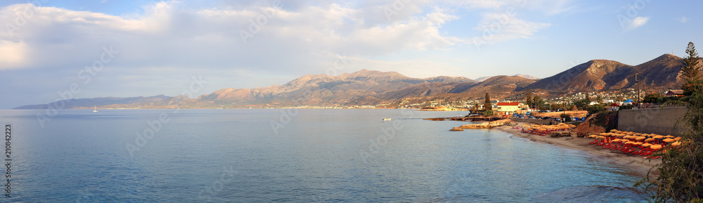Panorama of Hersonissos town with evening with a soft sunset glow in Crete, Greece and mountains.