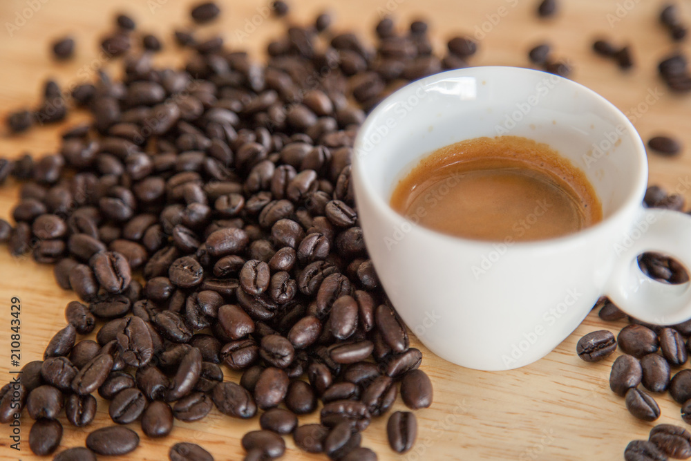 A cup of espresso on coffee beans on wooden table. A cup of espresso on coffee beans on wooden table.