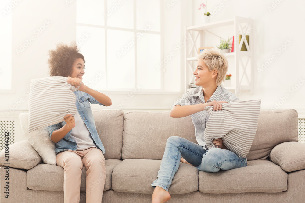 Two young women having pillow fight on sofa