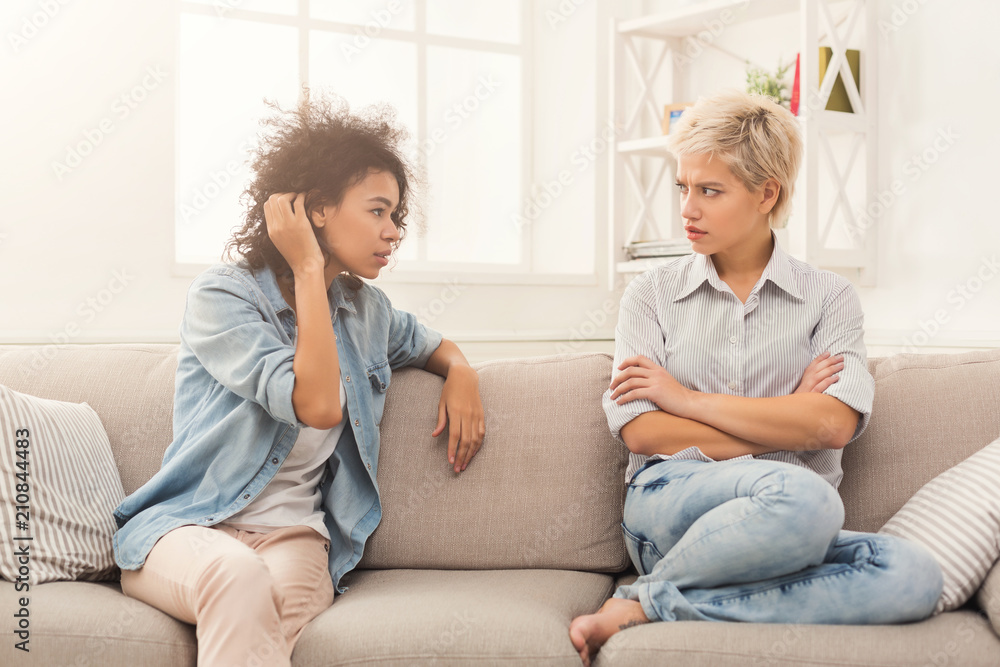 Two female friends sitting on sofa and arguing Two female friends sitting on sofa and arguing