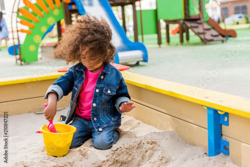 Cuadro en lienzo curly african american little child playing with plastic scoop and bucket in san