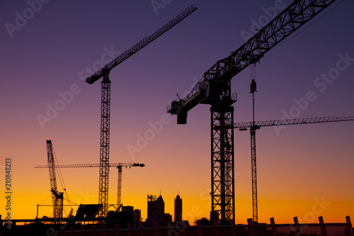 Silhouette cranes against a blue and orange sky