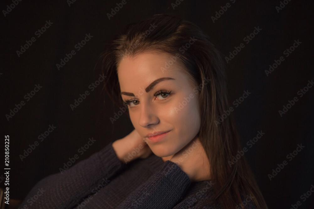 Beautiful young girl wearing sweater posing on black studio background touching her head with hand Beautiful young girl wearing sweater posing on black studio background touching her head with hand