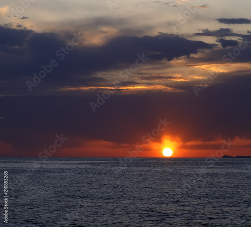 Bright colorful sunset on sea with beautiful clouds