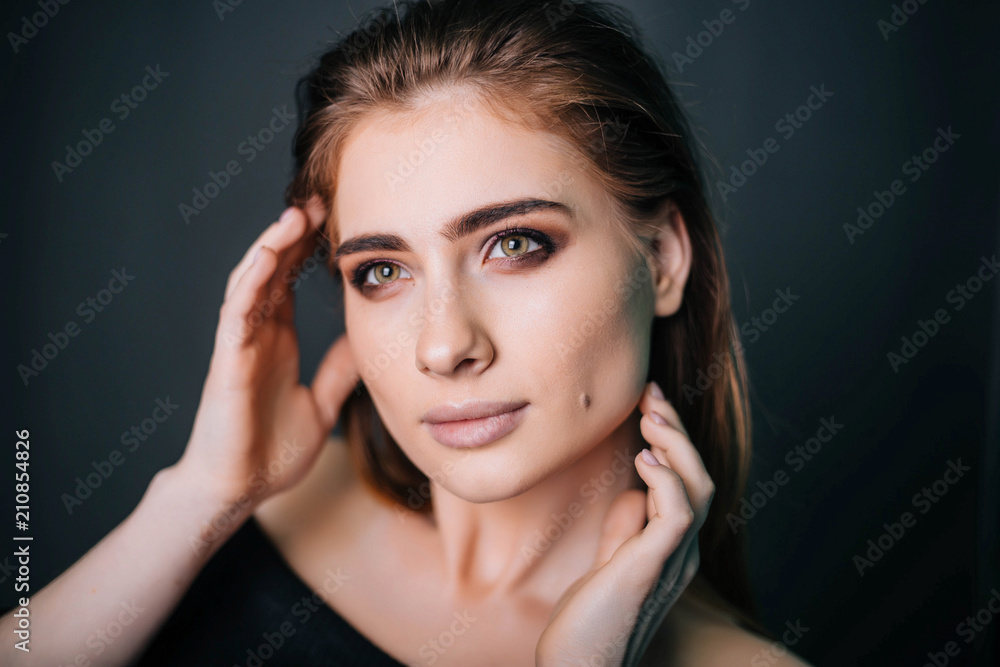 beauty portrait. Studio portrait of a beautiful girl on a gray background. Good make-up. Face close-up	