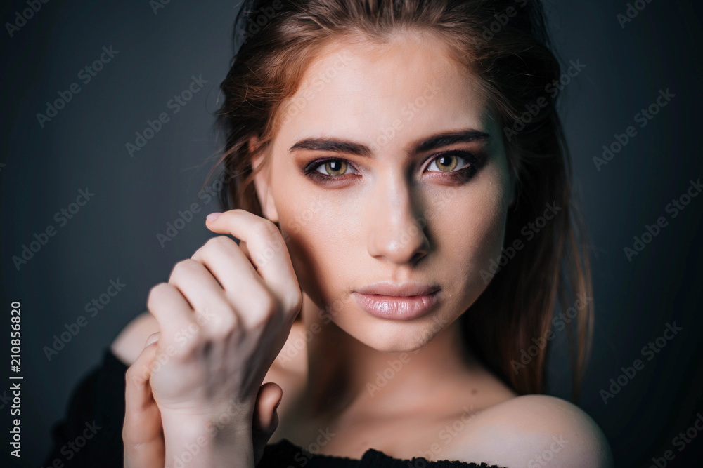 Fototapeta premium beauty portrait. Studio portrait of a beautiful girl on a gray background. Good make-up. Face close-up