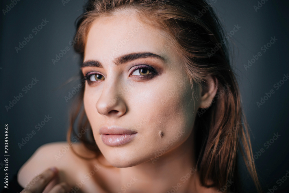 Fototapeta premium beauty portrait. Studio portrait of a beautiful girl on a gray background. Good make-up. Face close-up