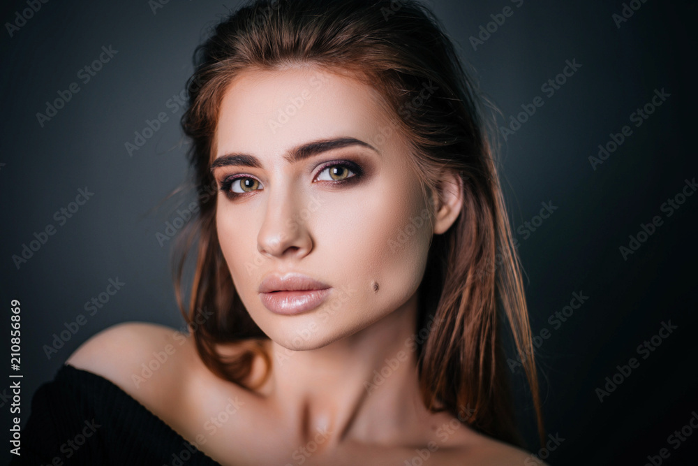 Fototapeta premium beauty portrait. Studio portrait of a beautiful girl on a gray background. Good make-up. Face close-up