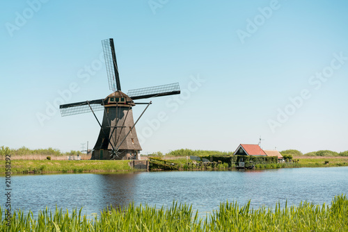 Windmill and water canal at sunny day in Kinderdijk, southern Holland. © juhrozian