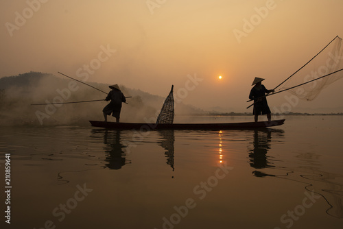 Canvas-taulu Fisherman is fishing in the river while sunset.