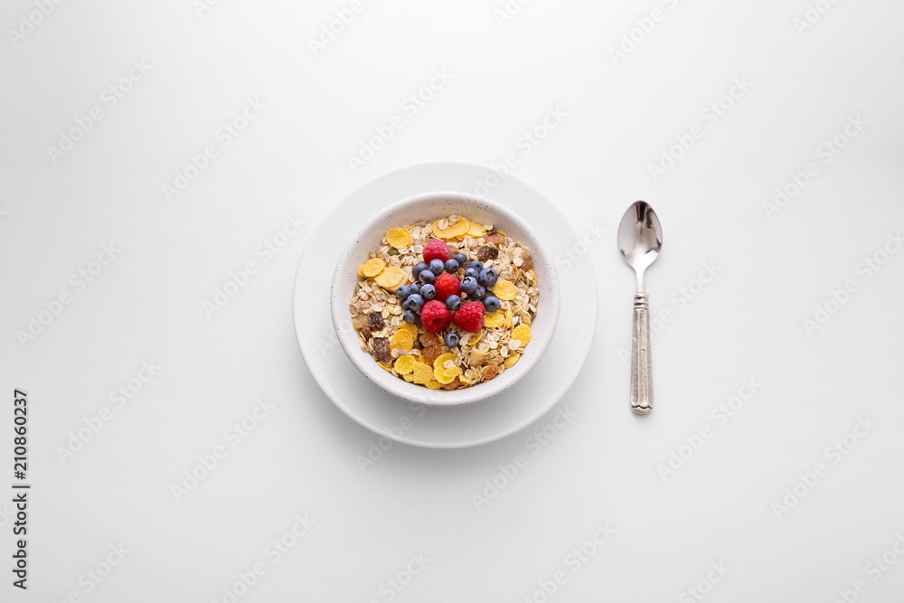 Muesli cereal breakfast with berry fruit in a white bowl with a spoon on the side viewed directly from above. Fresh rich in fiber granola dish viewed from above. Top view. Copy space Muesli cereal breakfast with berry fruit in a white bowl with a spoon on the side viewed directly from above. Fresh rich in fiber granola dish viewed from above. Top view. Copy space