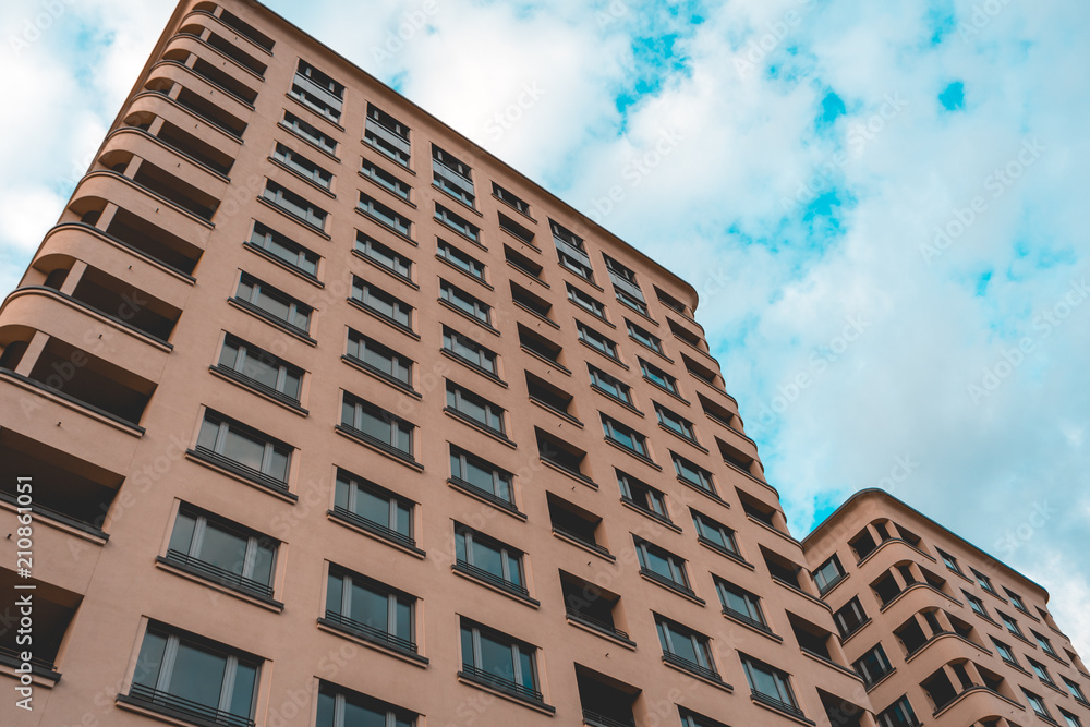 warm colored apartment building from the low angle view near potsdamer platz with a fluffy cloud background warm colored apartment building from the low angle view near potsdamer platz with a fluffy cloud background