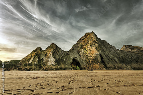 Dramatic sky over the monolithic Three Cliffs on the Gower peninsula, a landmark beach and a haven for rock climbers.
