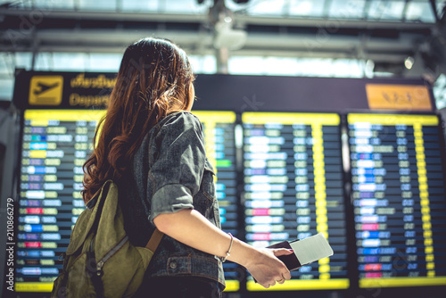 Beauty female tourist looking at flight schedules for checking take off time. People and lifestyles concept. Travel and Happy life of single woman theme. Back view portrait.