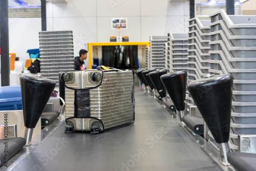 Suitcase on luggage conveyor belt at baggage  handling belt conveyor system at check in desk in airport. Baggage is running on the conveyor belt through an airport safety system.