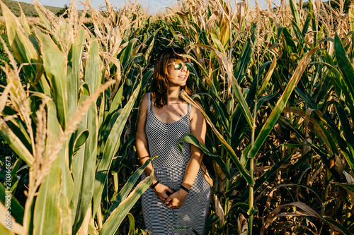 Young pretty woman standing in a green and yellow corn field. She is very happy  relaxed and carefree. Feel concept. Lifestyle.