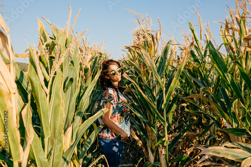 Young pretty woman standing in a green and yellow corn field. She is very happy  relaxed and carefree. Feel concept. Lifestyle.