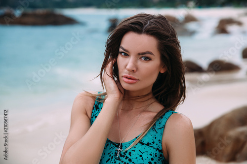 Portrait of a dark-haired beautiful woman, resting on the beach, the wind develops her long hair, the concept of rest, hotels, travel.