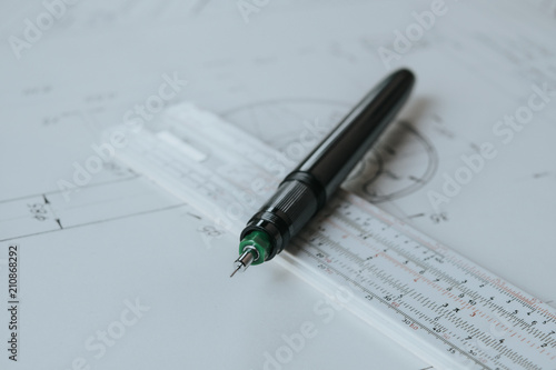 Technical pen (rapidograph) on slide rule and technical drawing. Engineer equipment.