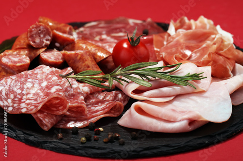 Food tray with delicious salami, ham, fresh sausages and herbs. Meat platter with selection