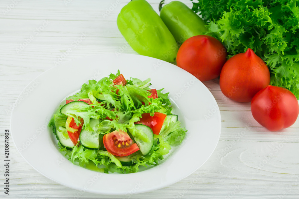 light summer salad of tomatoes, cucumbers and lettuce leaves, on a wooden background light summer salad of tomatoes, cucumbers and lettuce leaves, on a wooden background