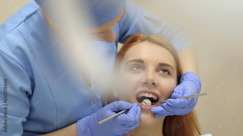 Female doctor examining a young girl's teeth in the dental office. Close-up of a woman dentist conducts dental examination and treatment for a young girl. The concept of health and dentistry. Female doctor examining a young girl's teeth in the dental office. Close-up of a woman dentist conducts dental examination and treatment for a young girl. The concept of health and dentistry.