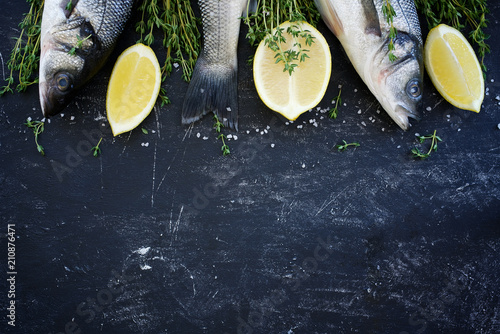 Raw uncooked seabass with thyme and lemon. Black shabby background
 photo