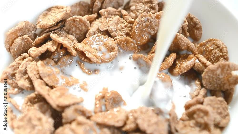 Food background and abstract: Pouring milk into a bowl of cornflakes, slow motion. Healthy breakfast of cornflakes with milk. Food background and abstract: Pouring milk into a bowl of cornflakes, slow motion. Healthy breakfast of cornflakes with milk.