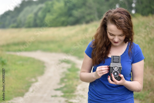 Beautiful young girl taking picture with vintage twin-lens reflex camera