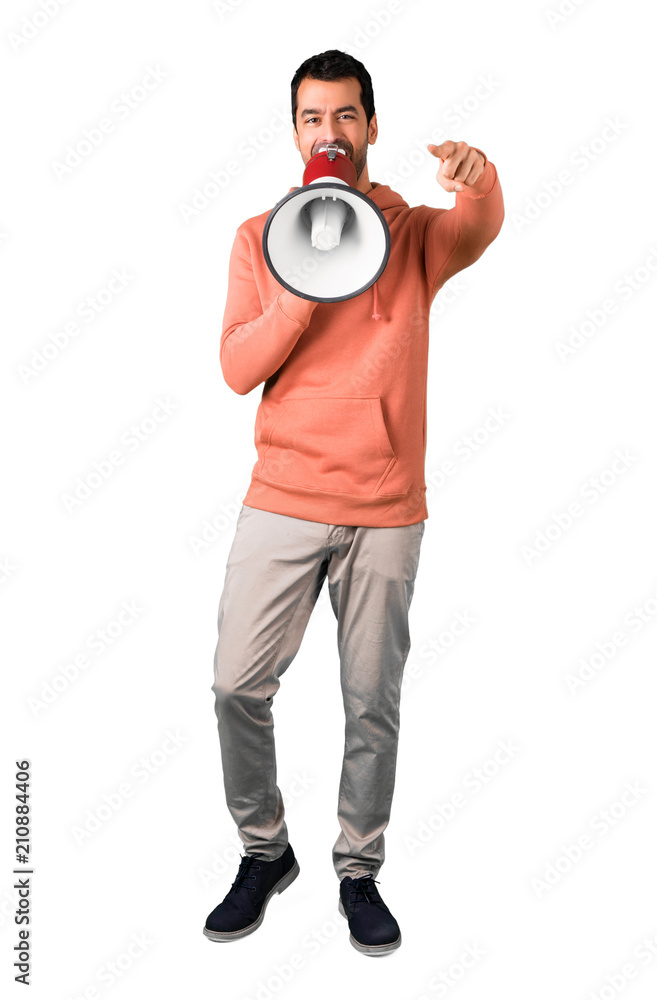 Full body of Man in a pink sweatshirt shouting through a megaphone to announce something while pointing to the front on isolated white background Full body of Man in a pink sweatshirt shouting through a megaphone to announce something while pointing to the front on isolated white background