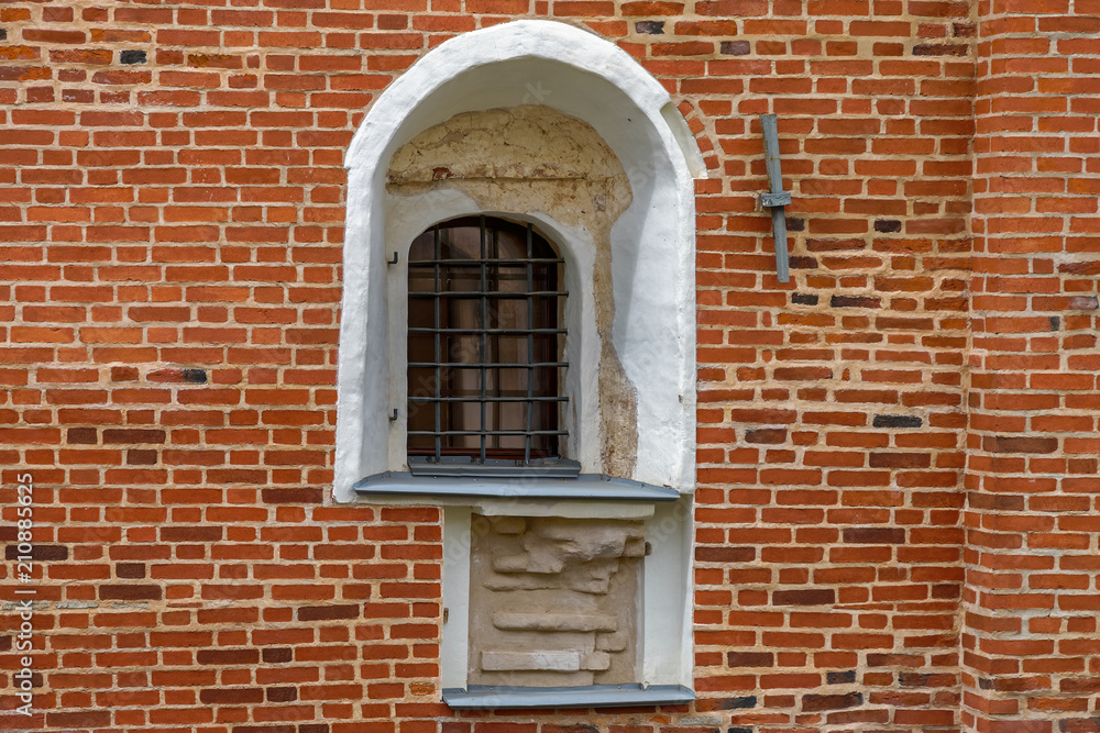 Arched window with iron grill on an ancient red brick wall. Arched window with iron grill on an ancient red brick wall.