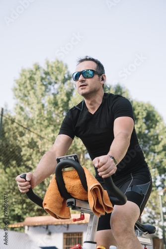 Man who performs physical activity with outdoor static bicycle