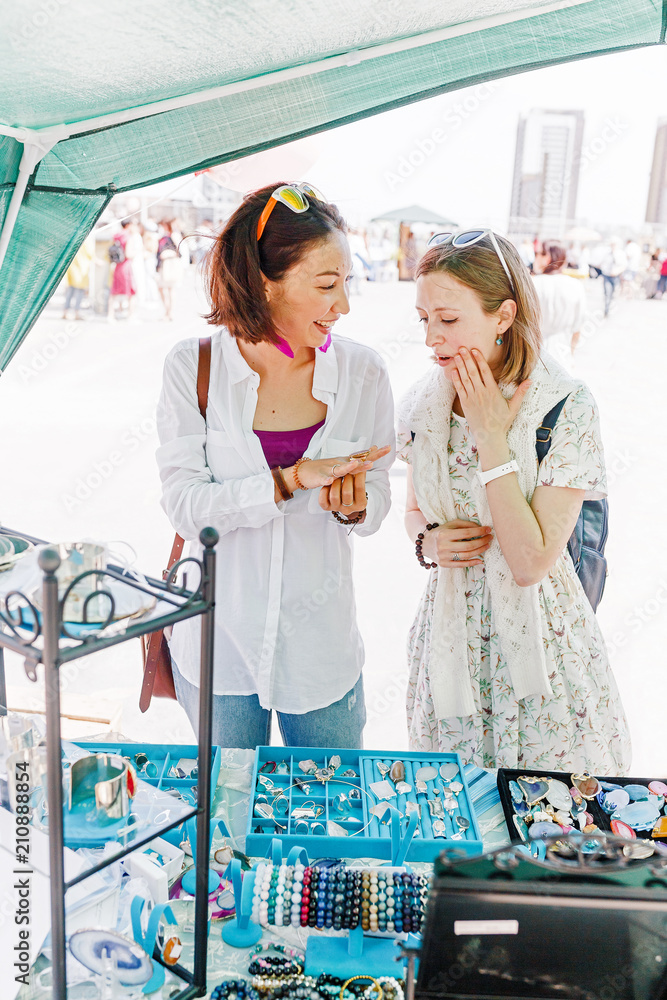 Φωτογραφία Two happy friends girls have fun while shopping in jewelry outdoor flea market