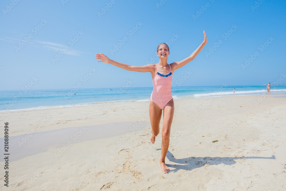 Girl in swimsuit runing and having fun on tropical beach