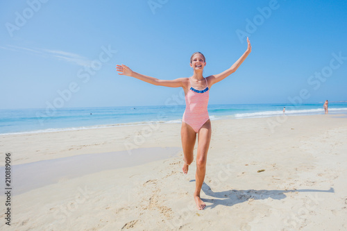 Girl in swimsuit runing and having fun on tropical beach photo