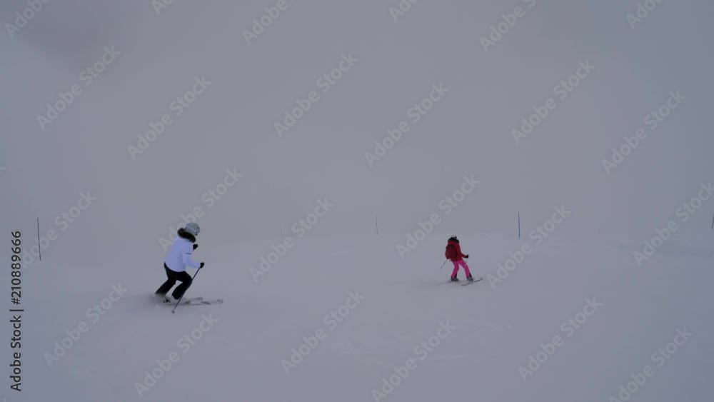 Two Female Skiers Skiing On The Mountain Downhill In Winter In Heavy Fog Two Female Skiers Skiing On The Mountain Downhill In Winter In Heavy Fog
