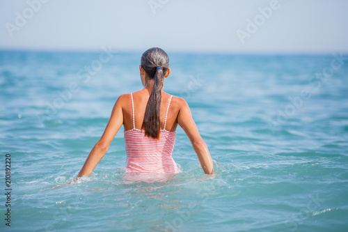 Girl in swimsuit having fun on tropical beach photo