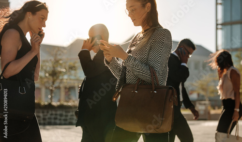 People busy using mobile phone while walking on street to office