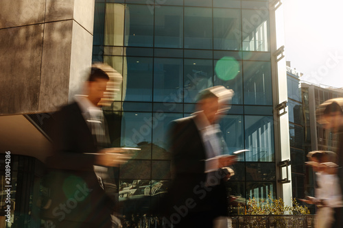 Business people using mobile phone while walking on street to of