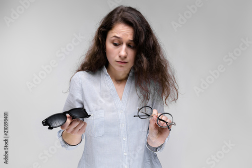 Young brunette girl with glasses. The girl is holding two pairs of glasses. photo