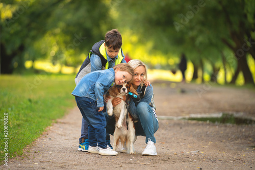 happy young mother with adorable kids and dog walking in park photo