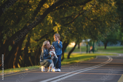 happy young mother with adorable kids and dog walking in park photo